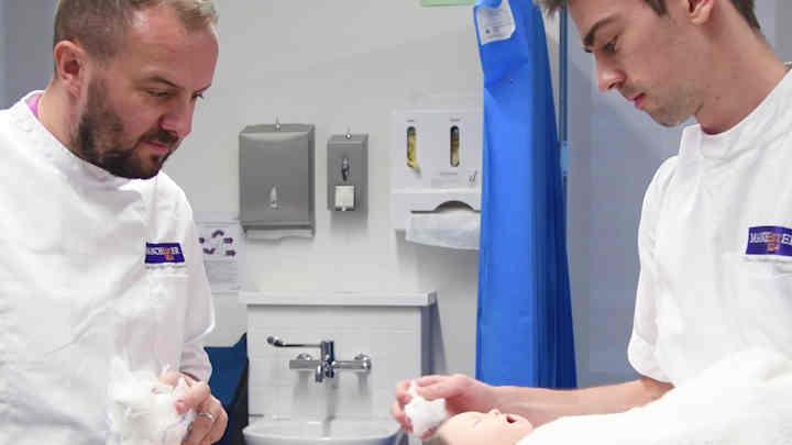 Student midwives learning how to wash a baby.