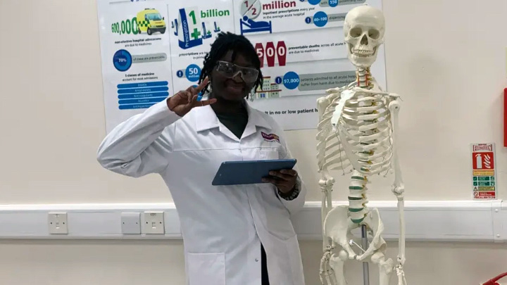Maureen Mensah standing beside a model of a human skeleton.