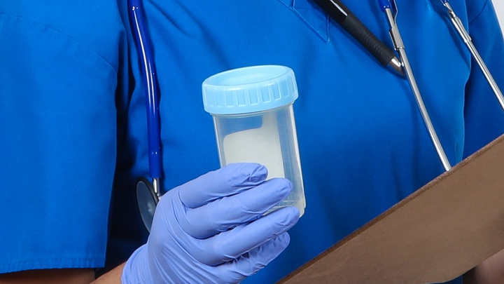 A scientist holding an empty sample pot.