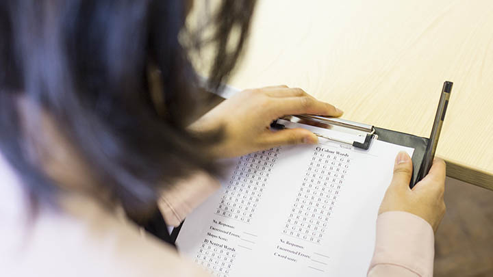 A student clipping an assessment sheet to a clipboard.