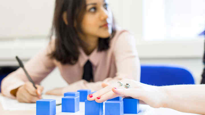 Psychology students conducting a psychology experiment using blue building blocks.
