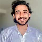 A portrait image of a smiling man wearing a light blue shirt with a shine.