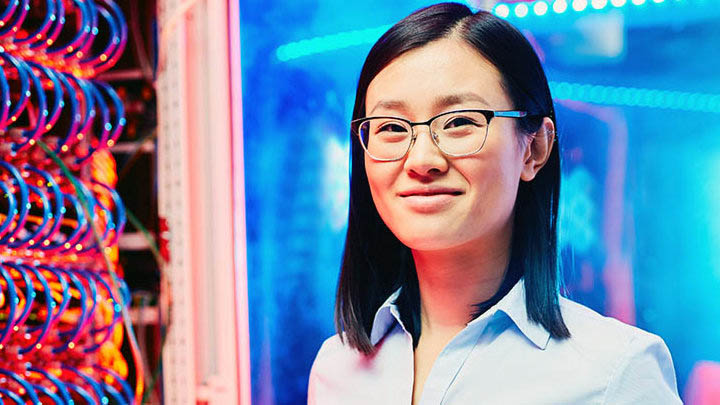 Researcher stood in front of a rack of processors at a high performance computing facility.