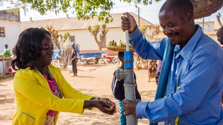 Two people at a standing water pump.