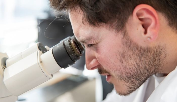 A postgraduate researcher looking into a microscope