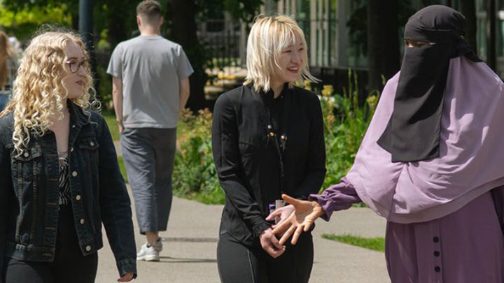 A group of postgraduate researchers at Manchester walking and talking together in a park.