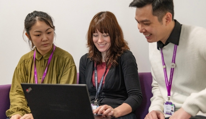 Two postgraduate students talking to a member of the Doctoral Academy team.