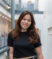 A female postgraduate researcher wearing black smiles at the camera.