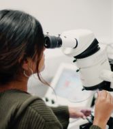 A female postgraduate researcher uses a high-tech microscope