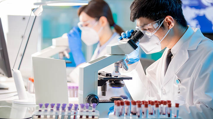 A researcher studying samples under a microscope.