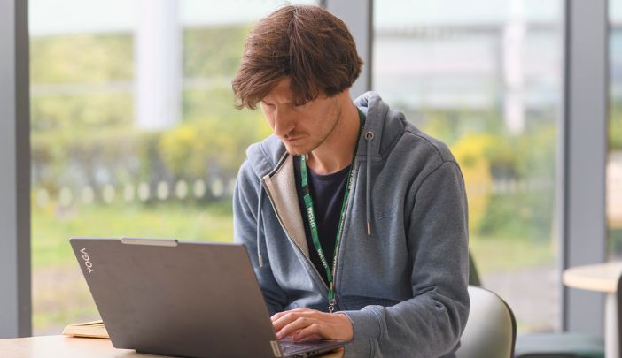 A researcher sitting side on works at his laptop