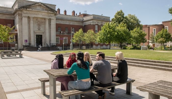 A group of students sat around a table outside a historic building on campus