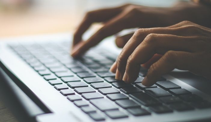 The hands of someone typing on a laptop.