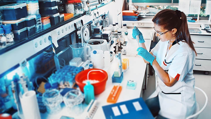 A researcher in the lab using a pipette.