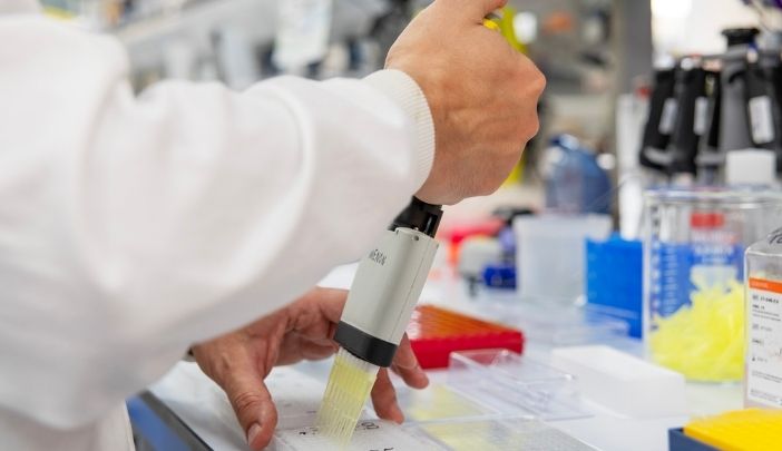 A close-up of postdoctoral researcher pipetting in the lab