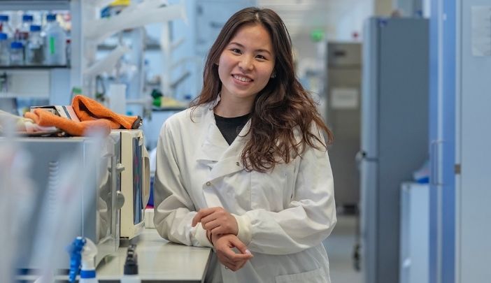 Researcher in a lab coat smiling looking at the camera