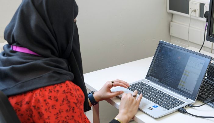 A postgraduate researcher working at their laptop