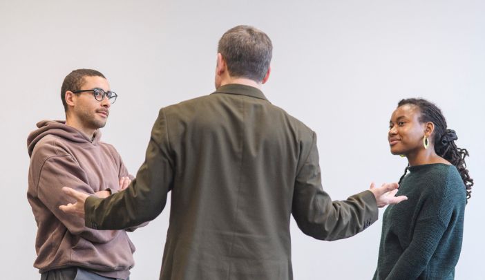 A coach stands between two postgraduate researchers during a training session 
