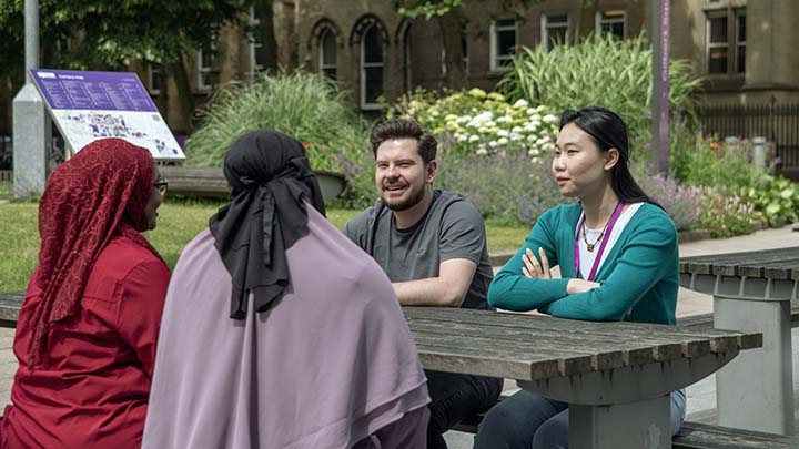 Postgraduate students sitting together outside at a table.