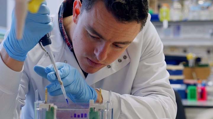 A researcher using a pipette in a lab.