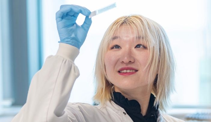 A researcher in a lab lifting a histograp in the air into the light and looking at it