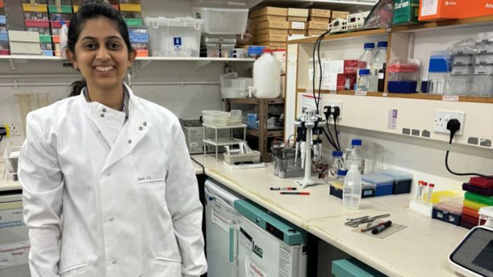 Dhruti, a PhD student, standing in a lab.