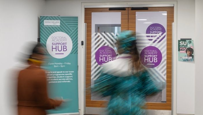 Blurred students walking into the Doctoral Academy support hub
