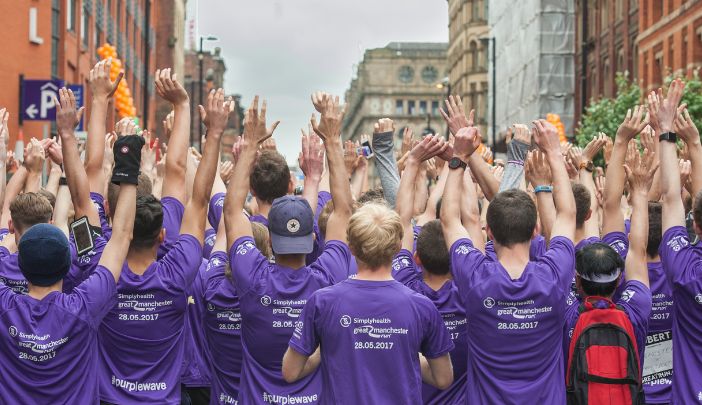 Students on the Purple Wave 10k cheering with their hands in the air
