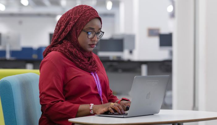 A postgraduate researcher typing on a laptop.