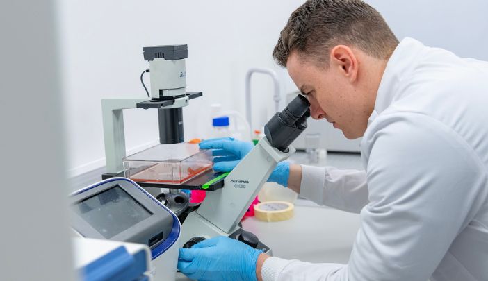 A researcher looking down a microscope