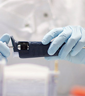 Blue gloved hands holding a black medical device.