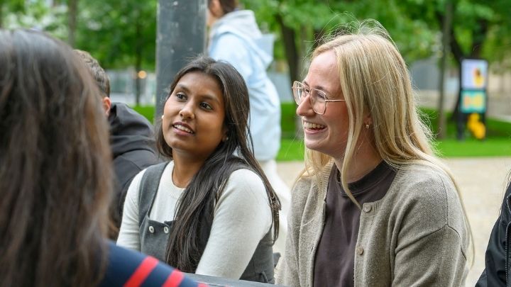 Georgia smiling sat chatting to fellow postgraduate researchers