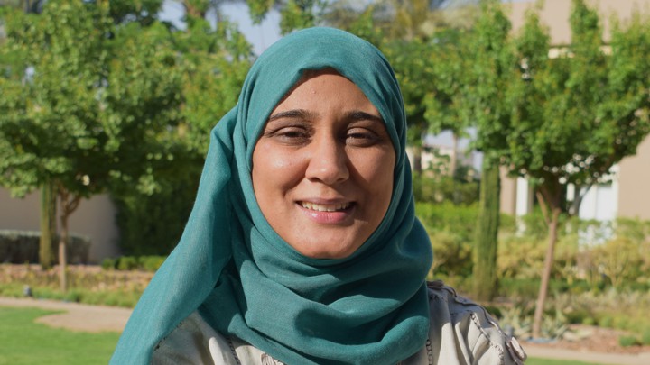 Suemyya (a woman wearing a headscarf standing in a garden).