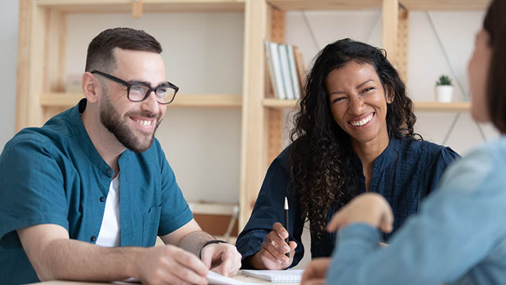 A social worker and patient in discussion, while a supervisor looks on.