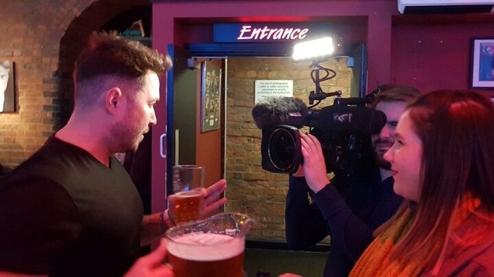 Student in a bar filming.