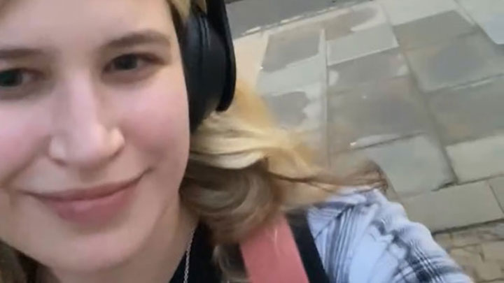 Close-up of SLT student Matilda smiling at the camera whilst wearing headphones.